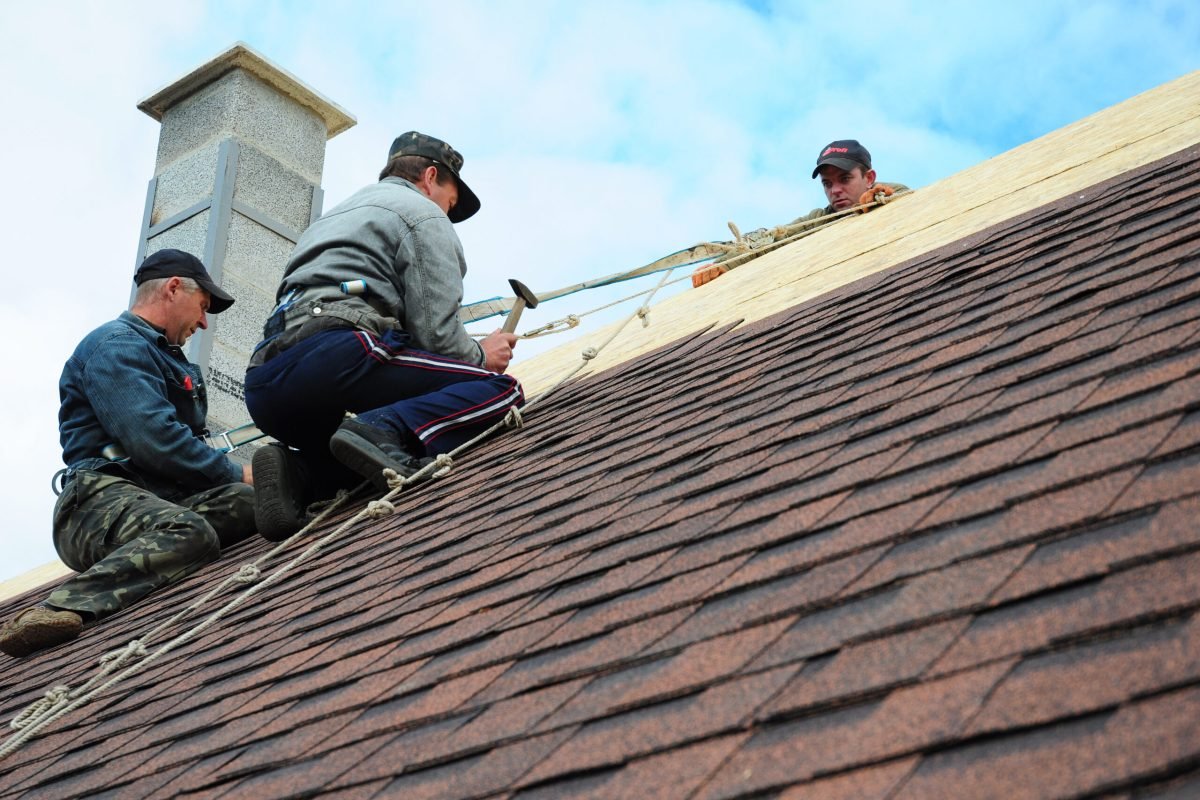 KIEV - UKRAINE MAY - 8  2017: Roofing Construction. Roofing Contractors Install New House Roofing with Asphalt Shingles Roofing Construction. Roofers with safety rope. Roofing Contractor.